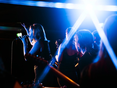 A band performing underneath blue stage lights for Sunday Sounds.