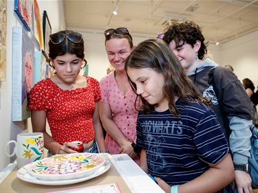 Children and their guardian looking at colourfully painted ceramics for Artz Blitz 2025.