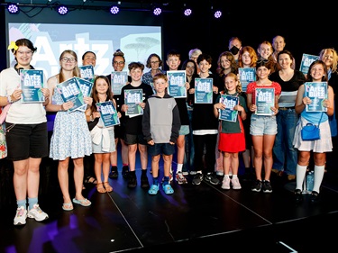 Artz Blitz 2025 awardees standing on a stage holding their certificates.