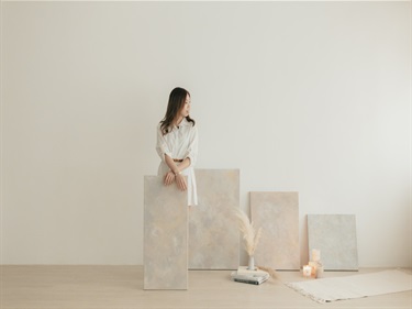 Artist Kiki Lo standing with artwork in a white studio space