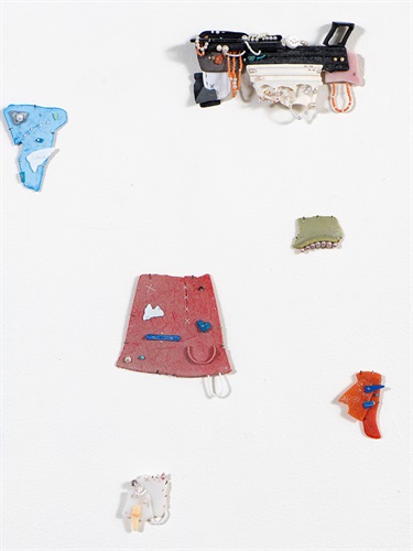 An installation image of 6 pieces of weathered plastic which have been constructed into assemblages of different coloured plastics, connected with thread, beads and pearls. The pieces are fragments which have been connected together in unusual ways, the discarded plastic is a focus in this image.