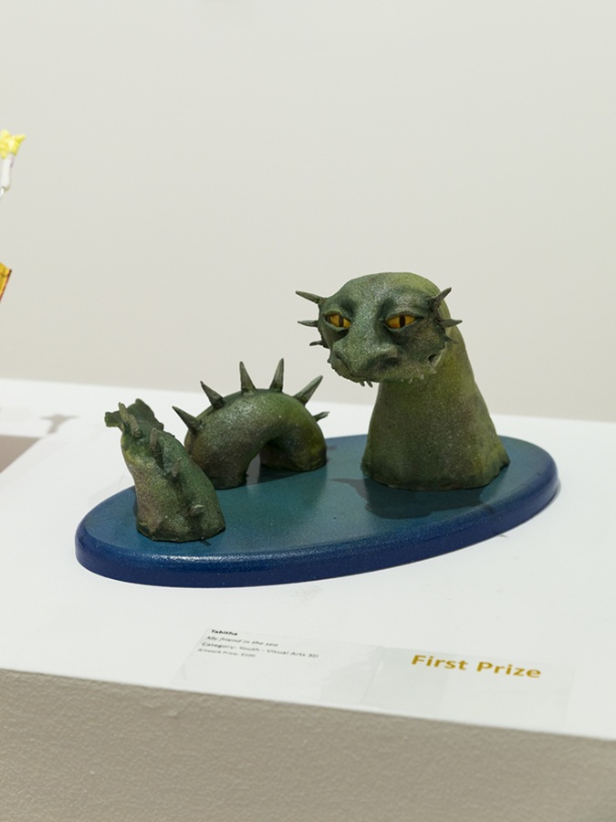 Sculpture of green monster coming out of a blue body of water