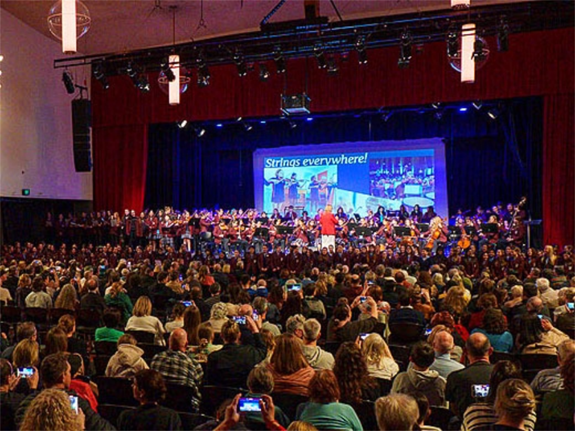 auditorium filled with audience and band members on stage