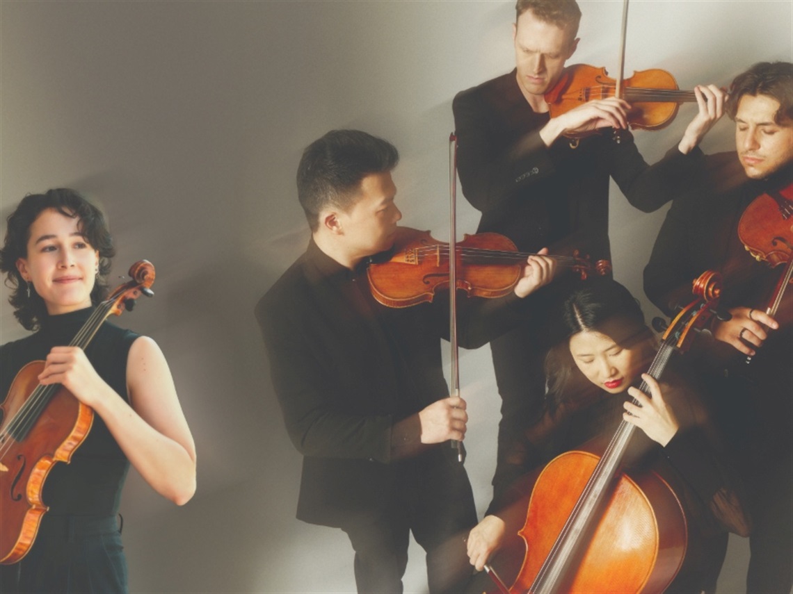 Five people play various chamber string instruments in a group.