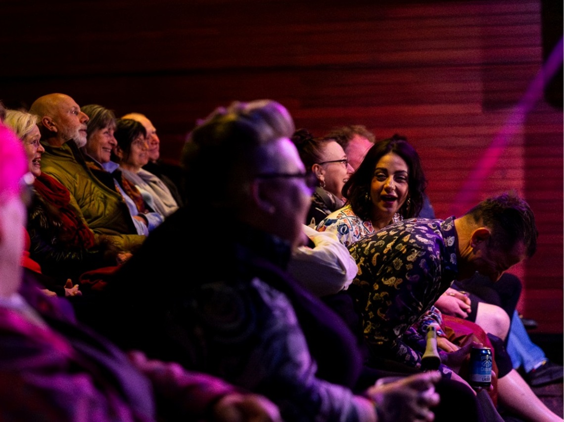 Various people in a theatre audience laughing.