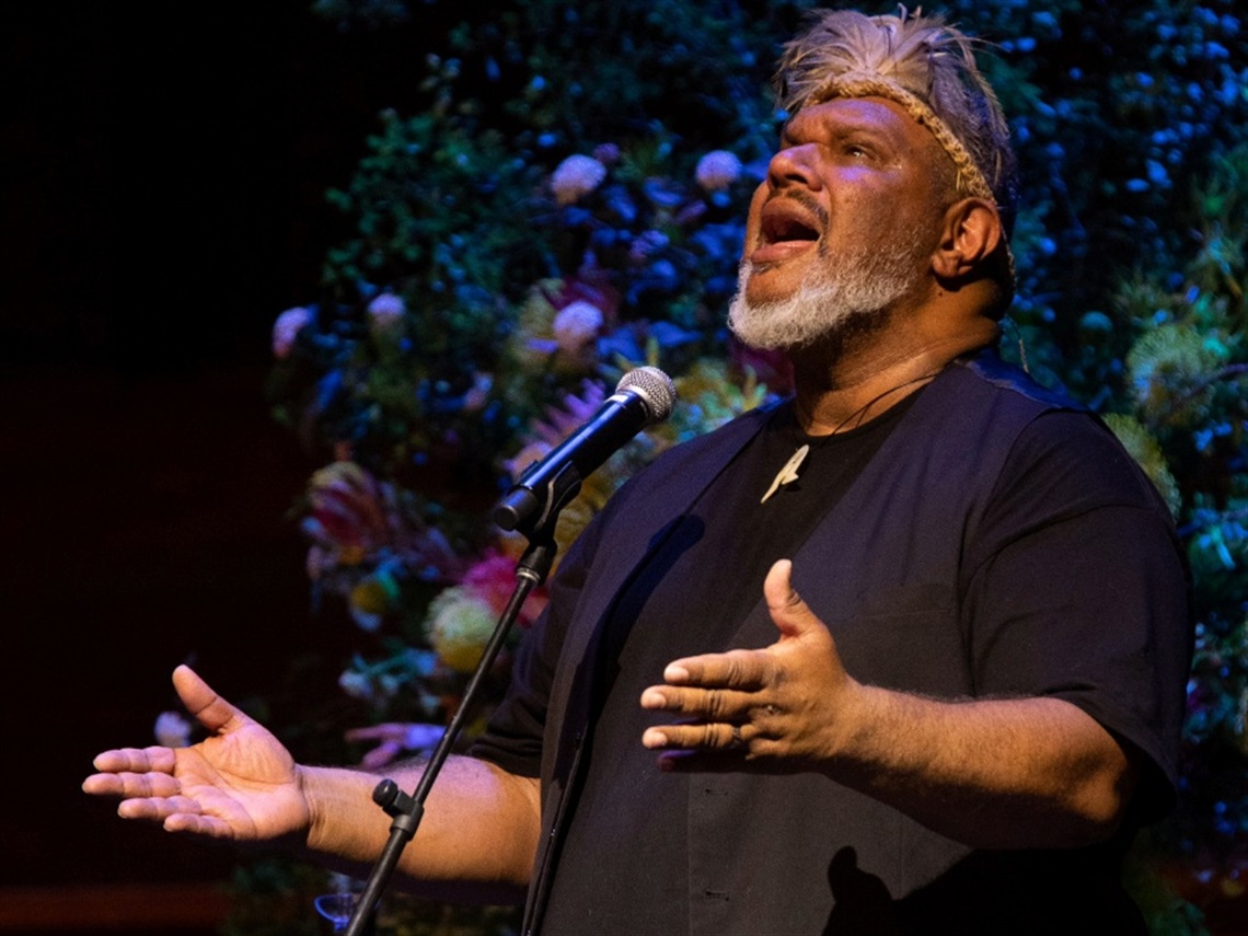 John Wayne Parsons, an Indigenous musical artist, standing in front of a microphone singing.