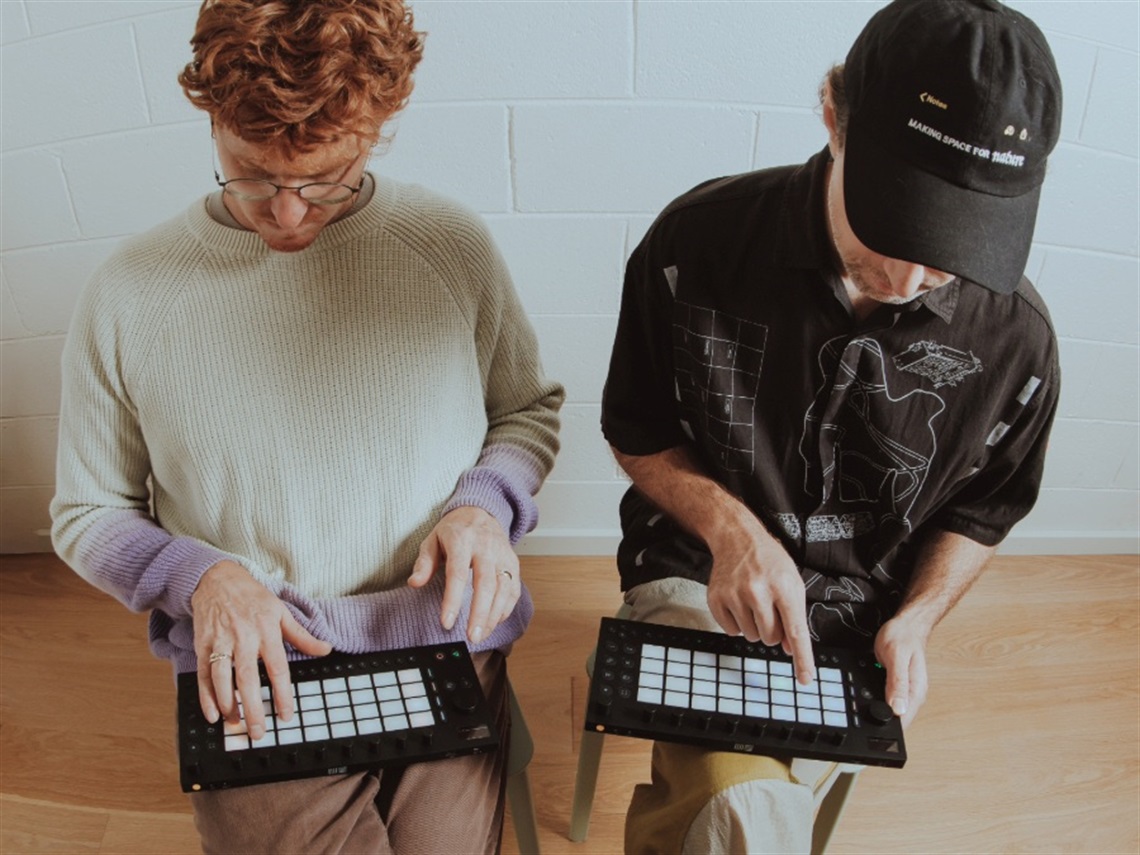 Two people using electronic music controllers.