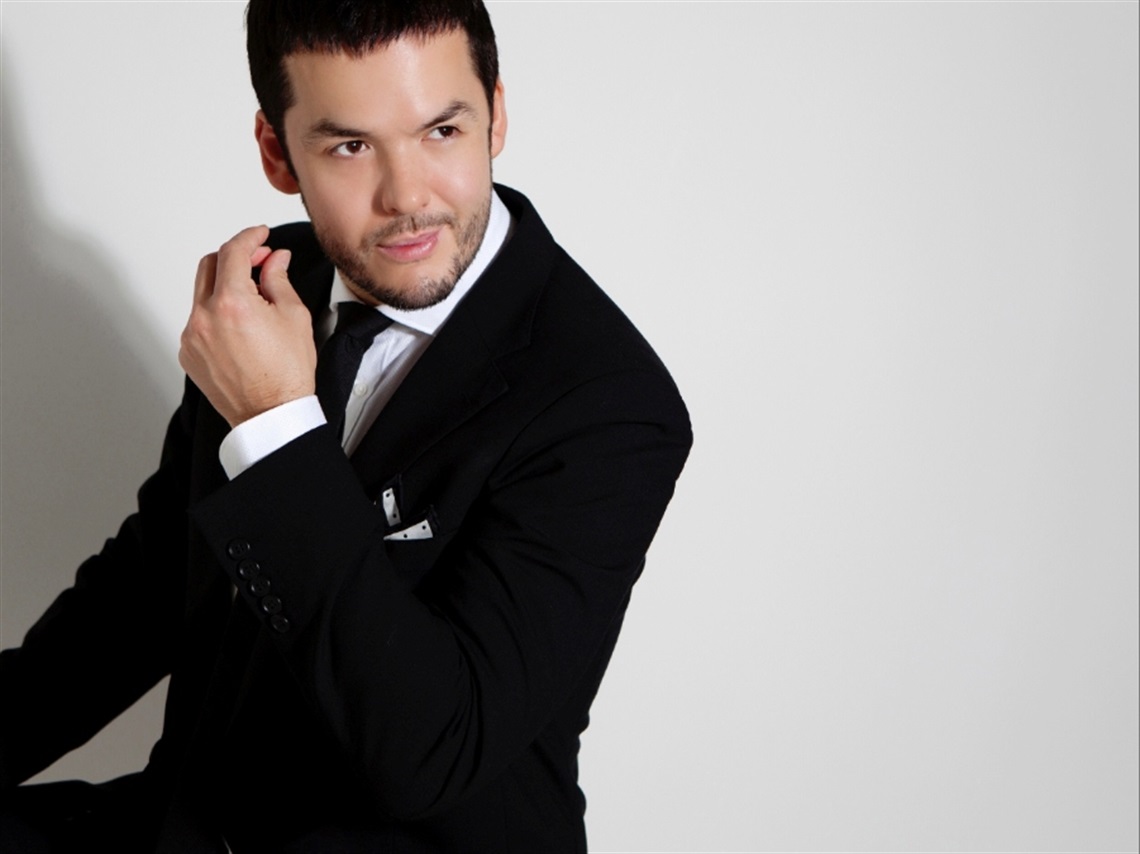 A man wearing a black suit with a black tie staring off into the right