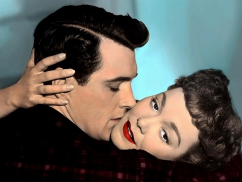 A man and woman embrace each other while the man kisses the woman's cheek