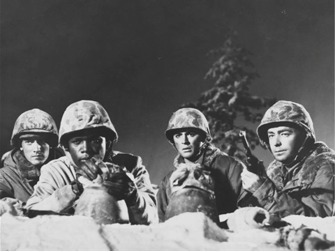 Four men behind rocks in military uniform with guns