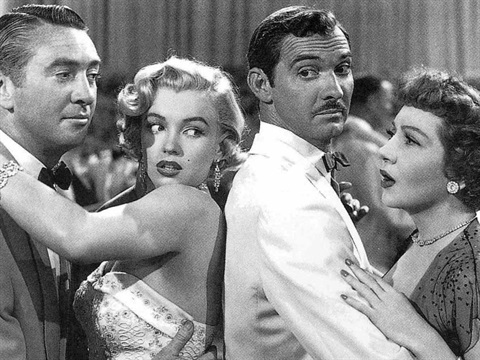 Two couples mid dance with the women looking at each other.