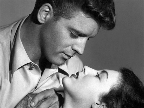 A man holds a woman in an embrace whilst staring down towards her