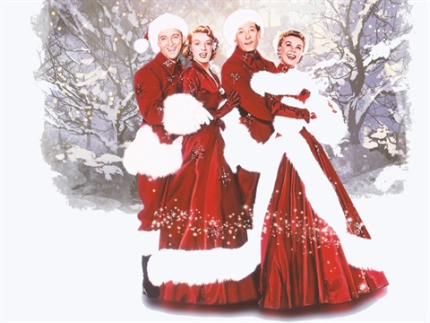 Four people stand together in the snow wearing red and white gowns