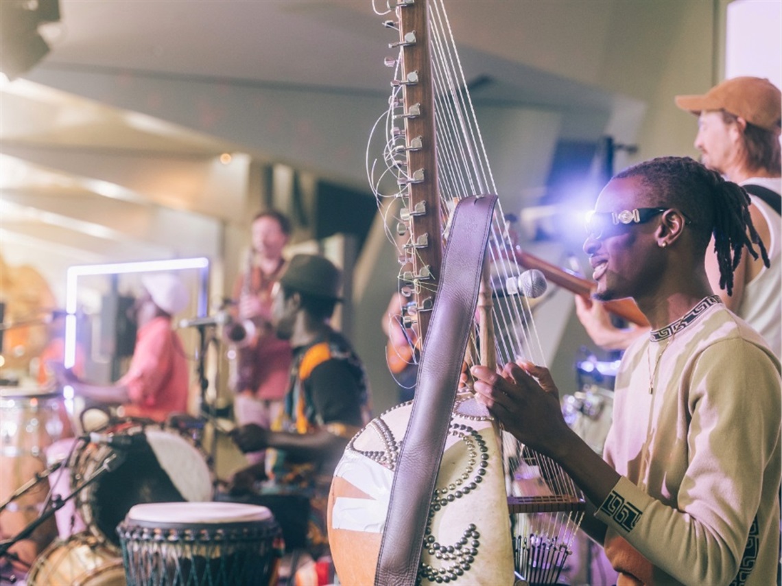 Men play on a stage with traditional instruments from the Senegal and Cuban regions.