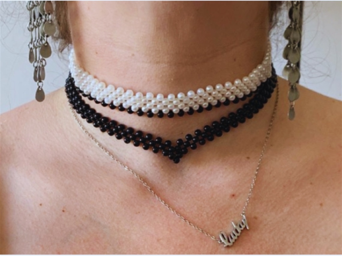 Close up of a neck with two beaded necklaces and a chain necklace