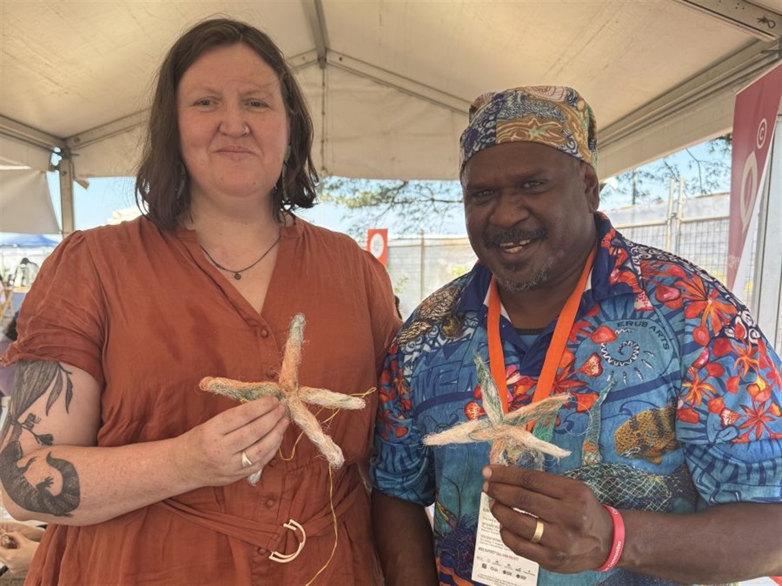 Two First Nations people each holding a handmade sea star from repurposed fishing nets