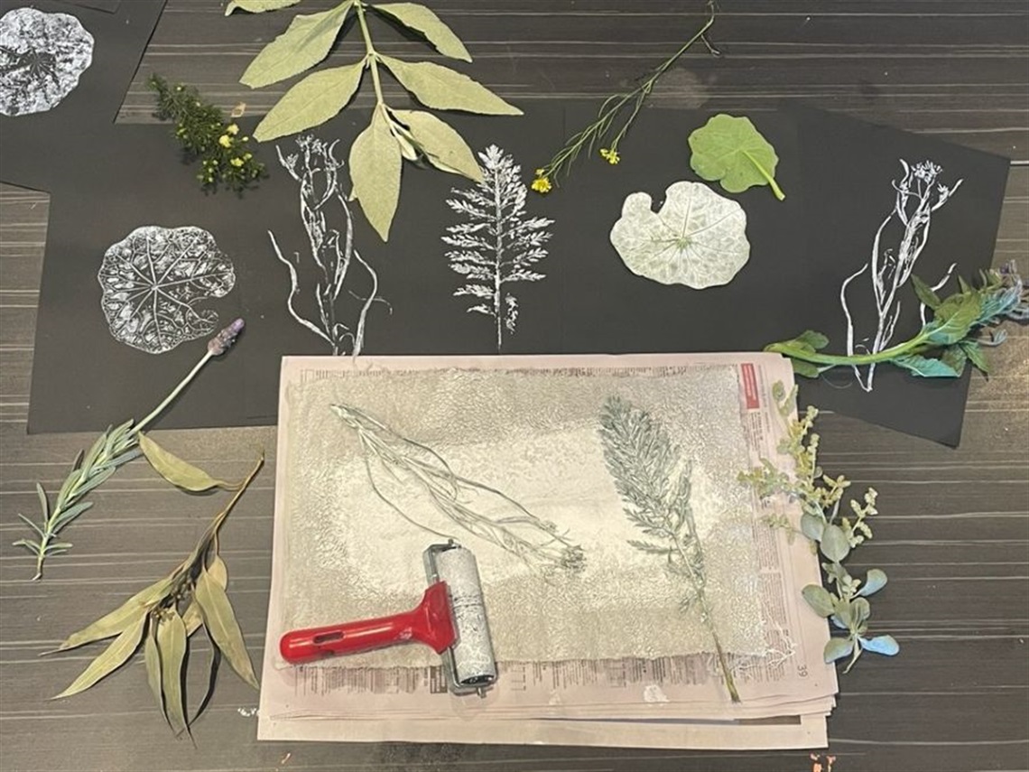 Paper with various leaves and botanicals and a hand roller.