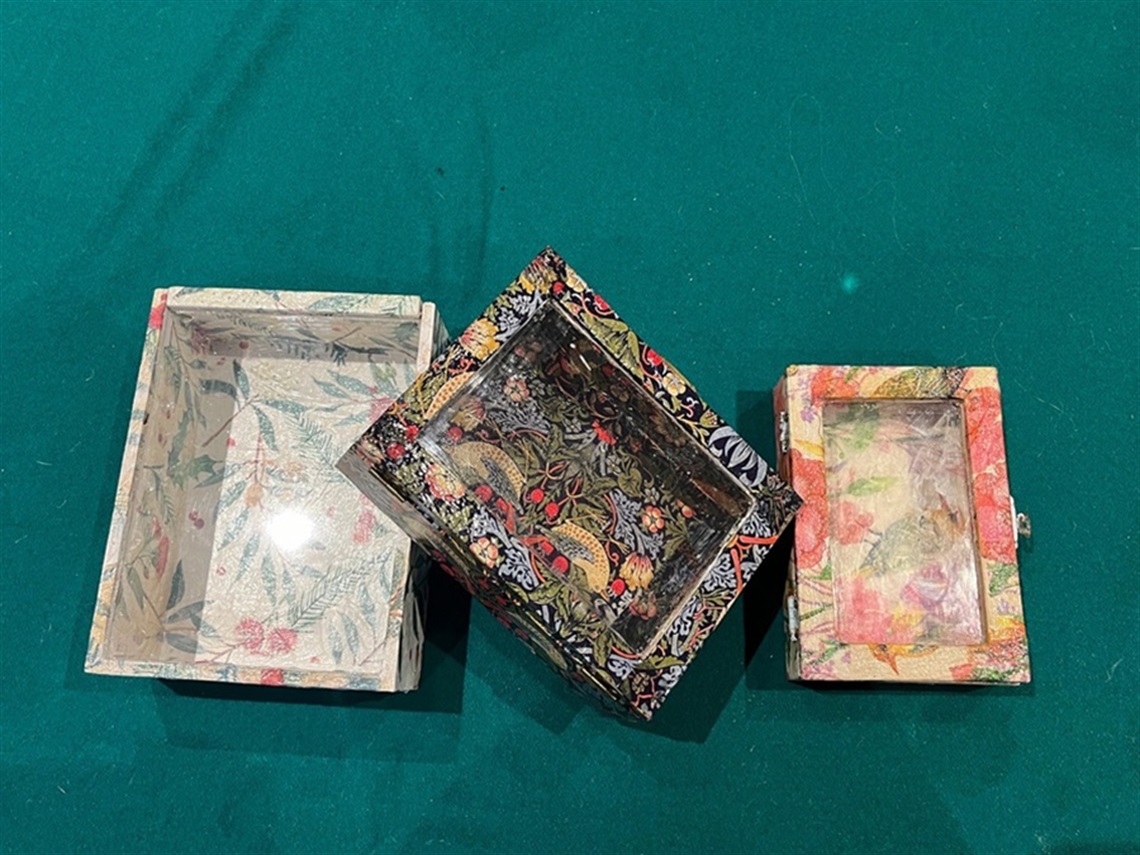 Three decoupage wooden boxes on a green background