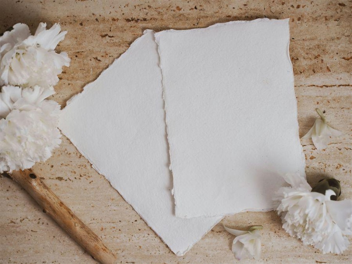 wooden table top with two sheets of handmade paper