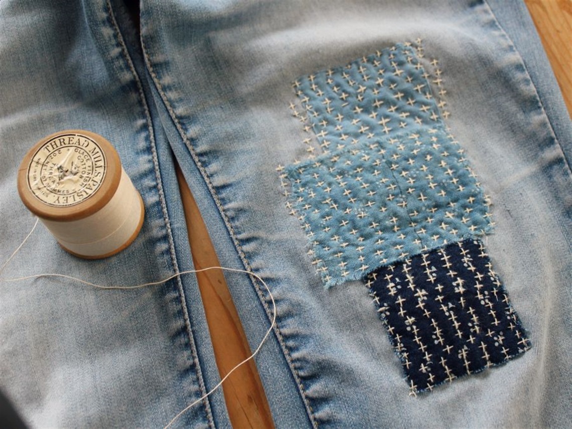 Three mended patches on a pair of blue jeans