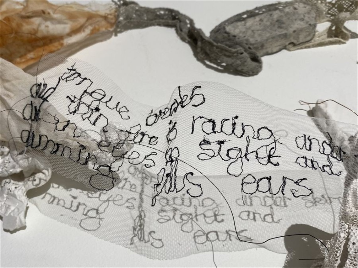 Artwork with hand-embroidered poetic text in black