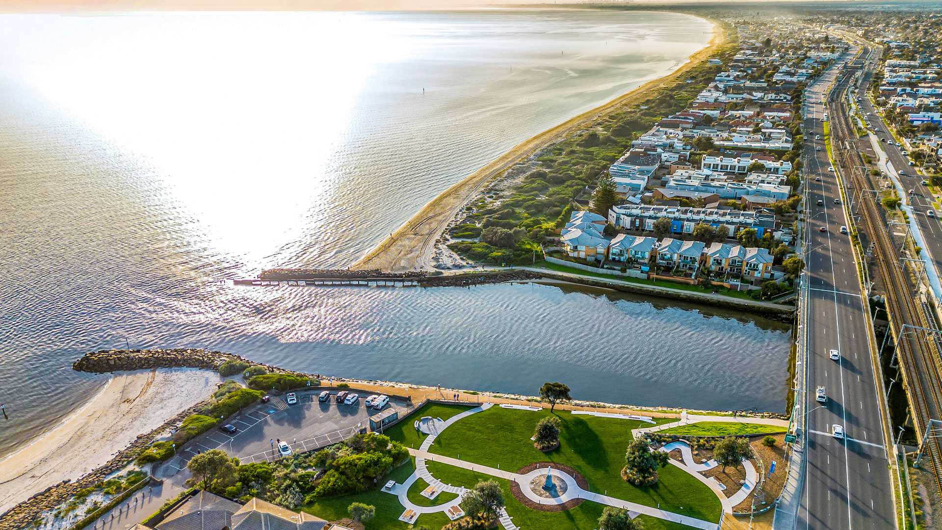 Aerial photograph showing Patterson River meeting the sea. Houses and parks surround the river and Nepean Highway can be seen on the right side of the photo