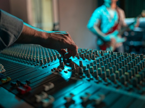 A sound board with hands turning nobs