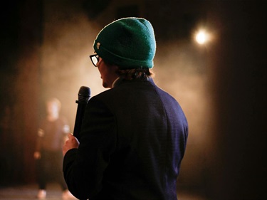 a palce-holder image of a person on stage holding a microphone